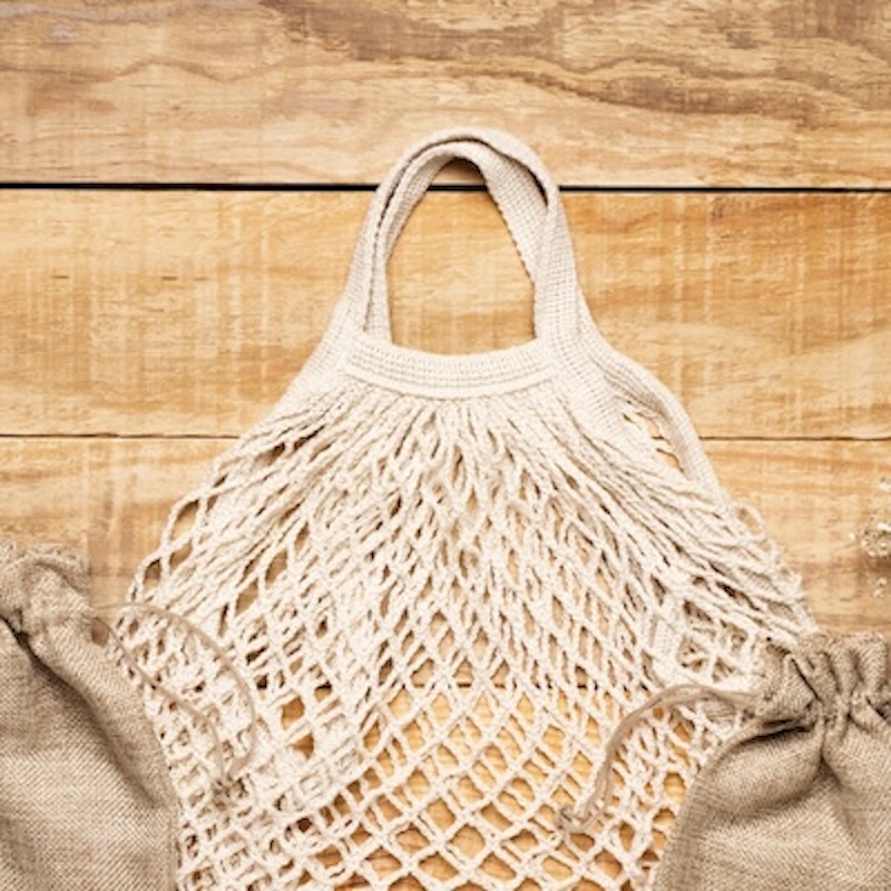Picture of crochet white mesh grocery bag against a wood backdrop