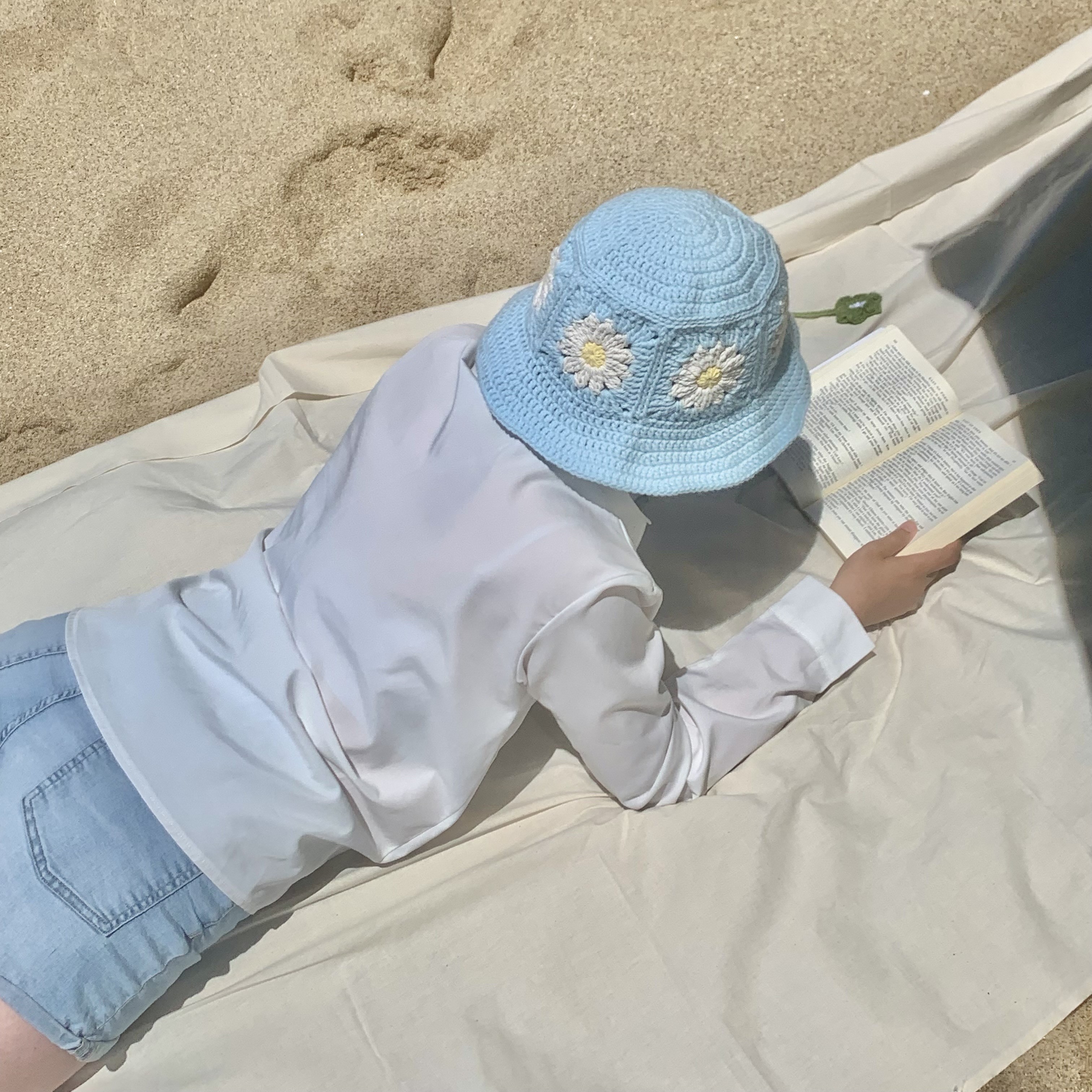 Angela reading with crochet bucket hat and bookmark at the beach
