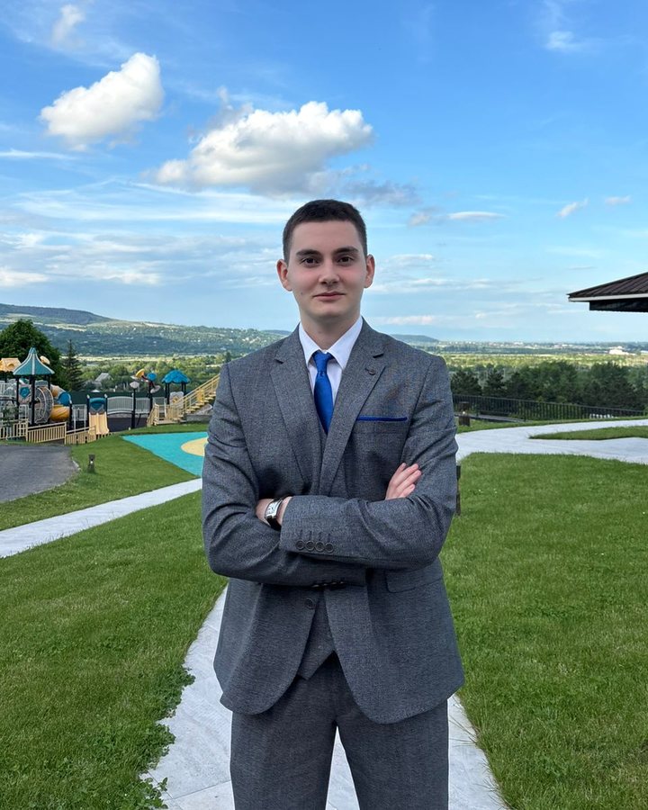 Demetre Bzekalava in a grey suit, standing outdoors